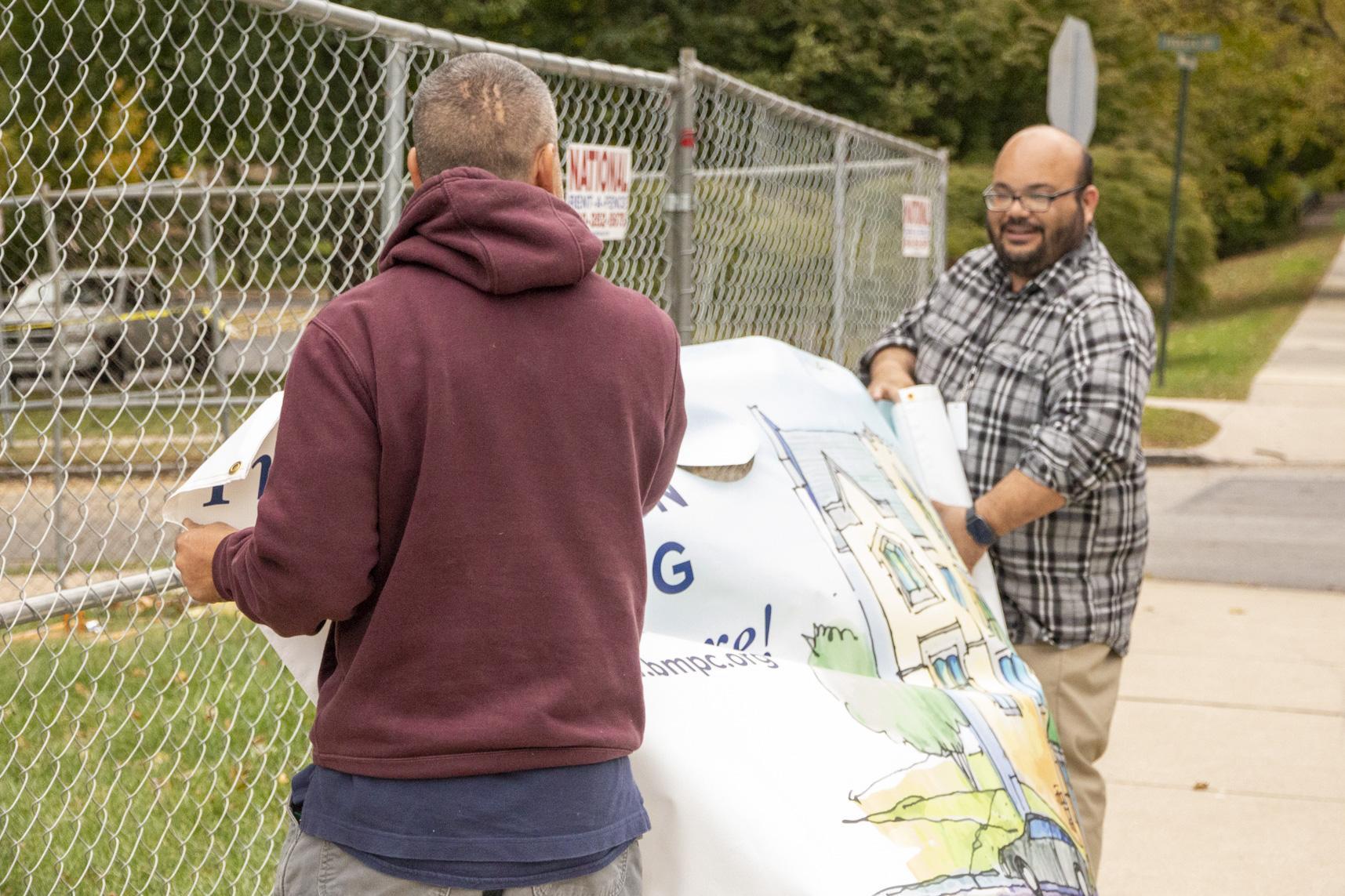 Rich and Howard hang a banner on the fence.