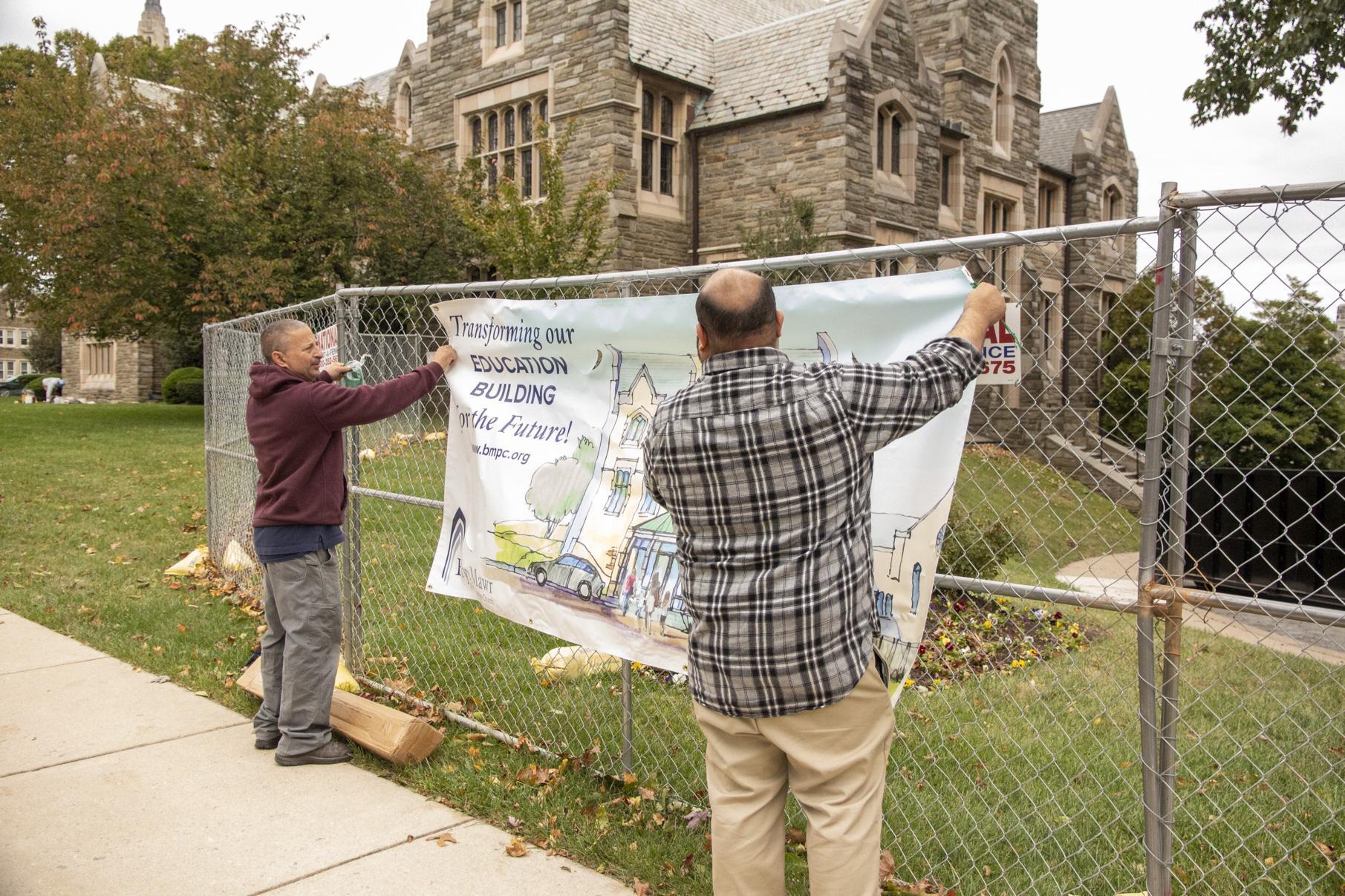 Rich and Howard hang a banner on the fence.