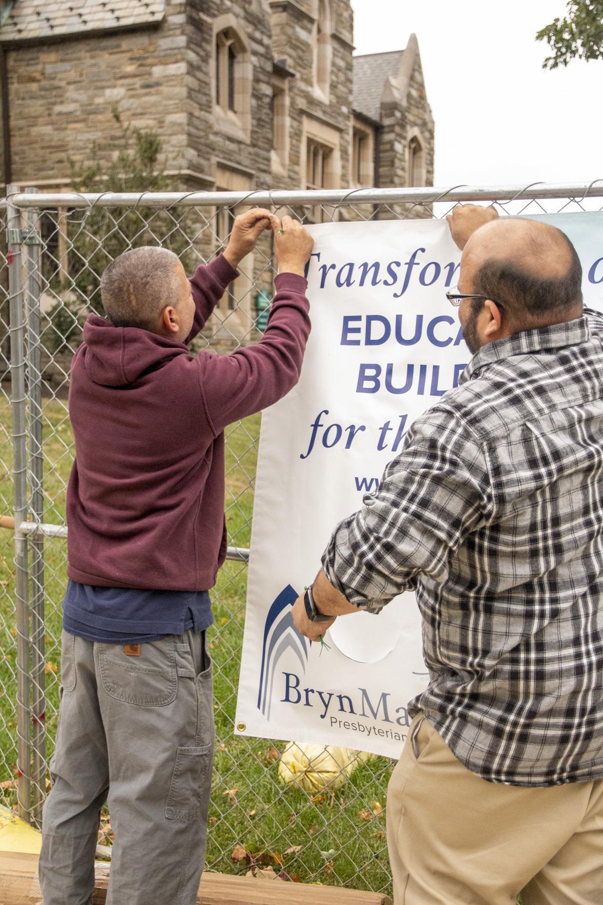 Rich and Howard hang a banner on the fence.