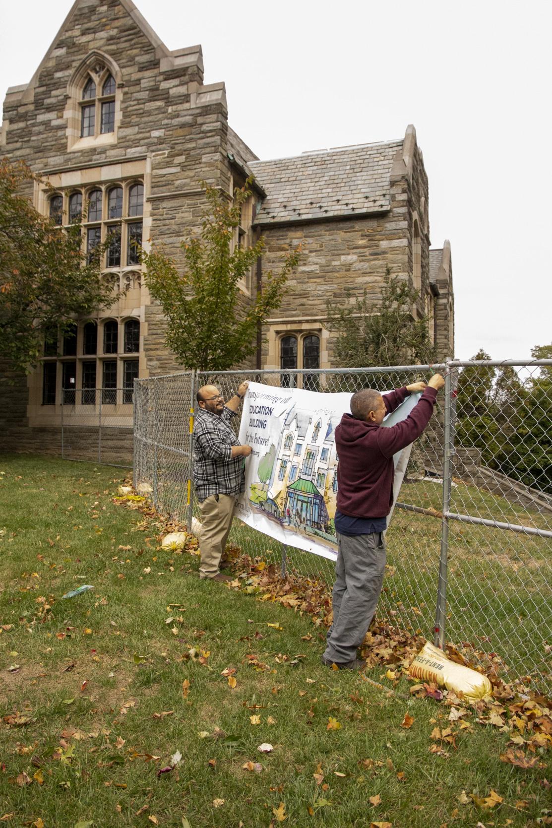 Rich and Howard hang a banner on the fence.