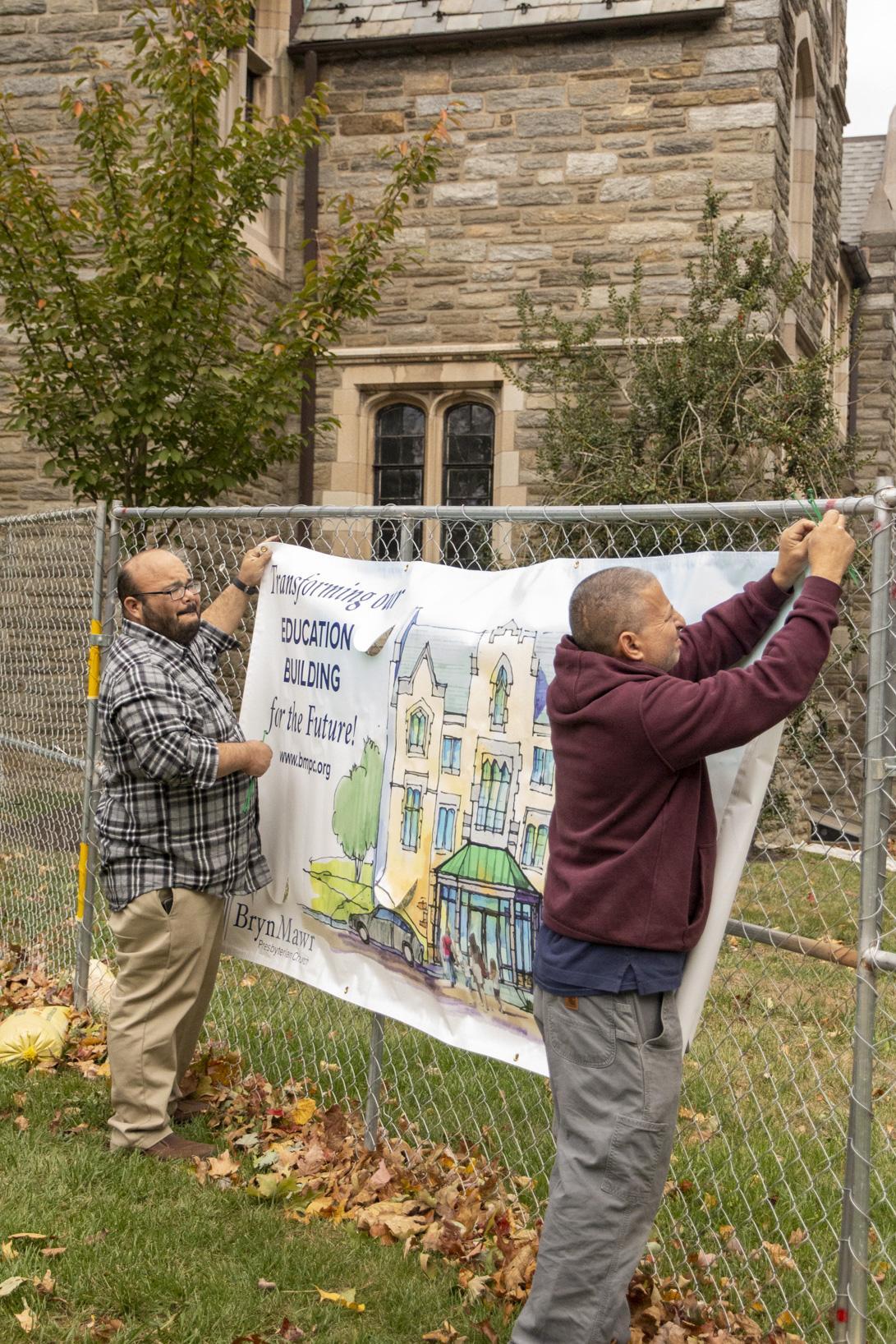Rich and Howard hang a banner on the fence.